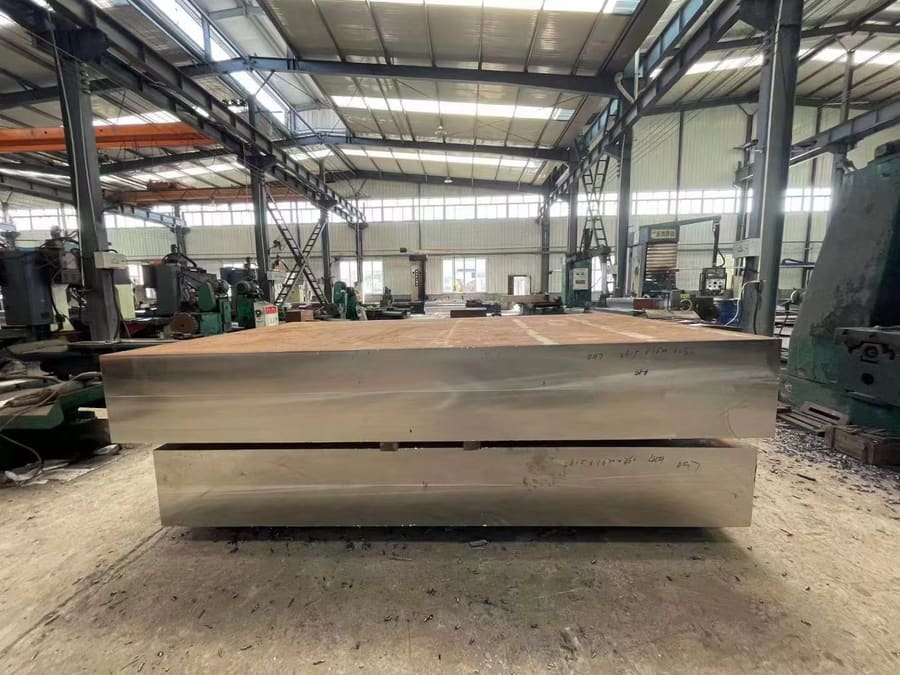 Large custom steel plate with dimensional markings on workshop floor