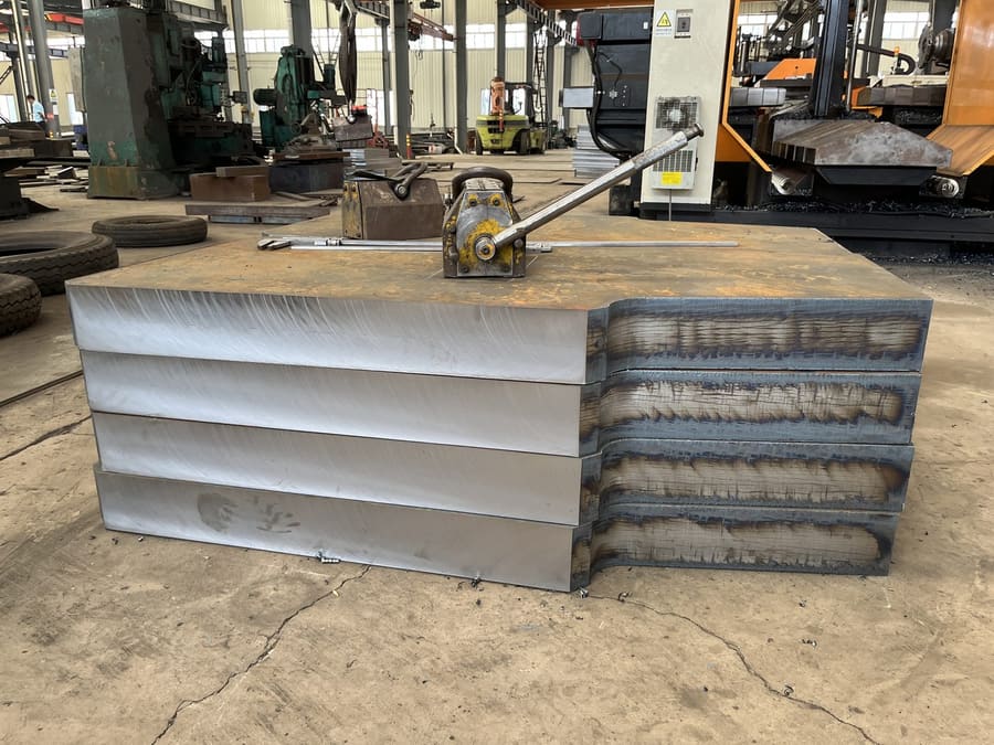 Stack of thick steel plates showing machined faces and cut edges