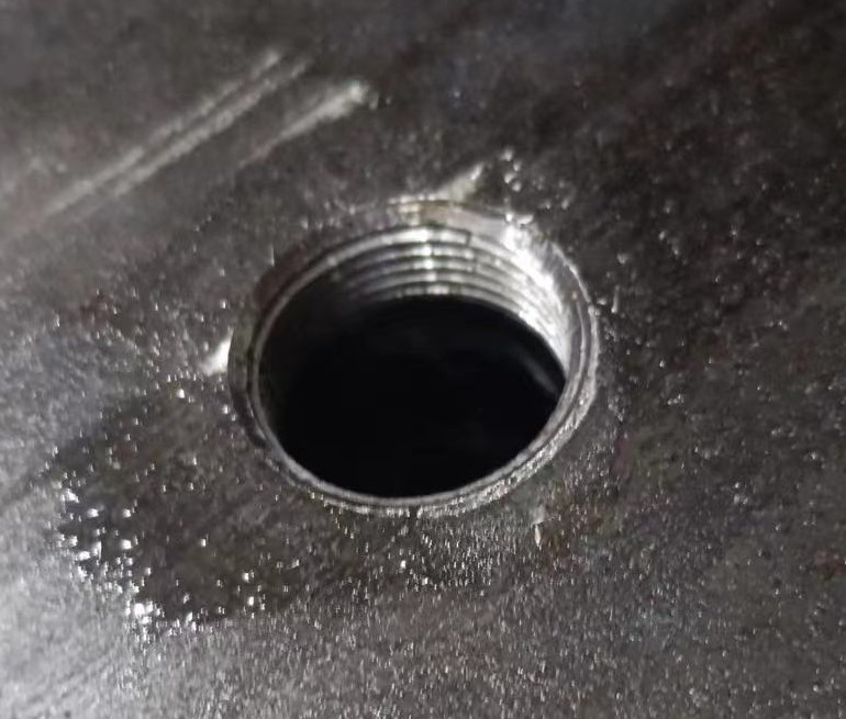 Close-up of drilled and threaded steel plate hole